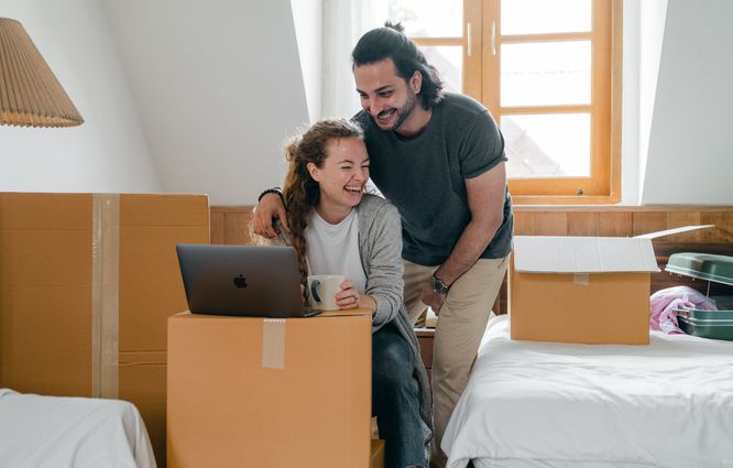 Couple laughing, computer, boxes, moving house, consultation